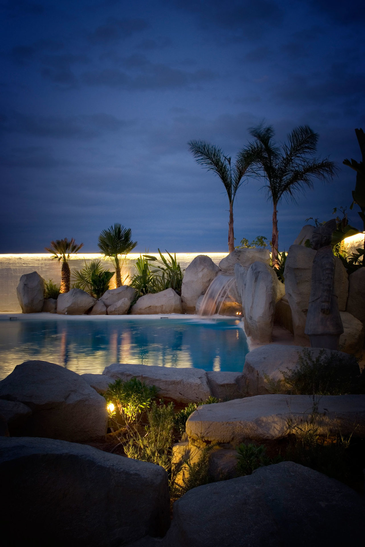 paisajismo y diseño piscina alicante estudio de interioristas Valencia piedras artificiales y palmeras iluminadas vista nocturna